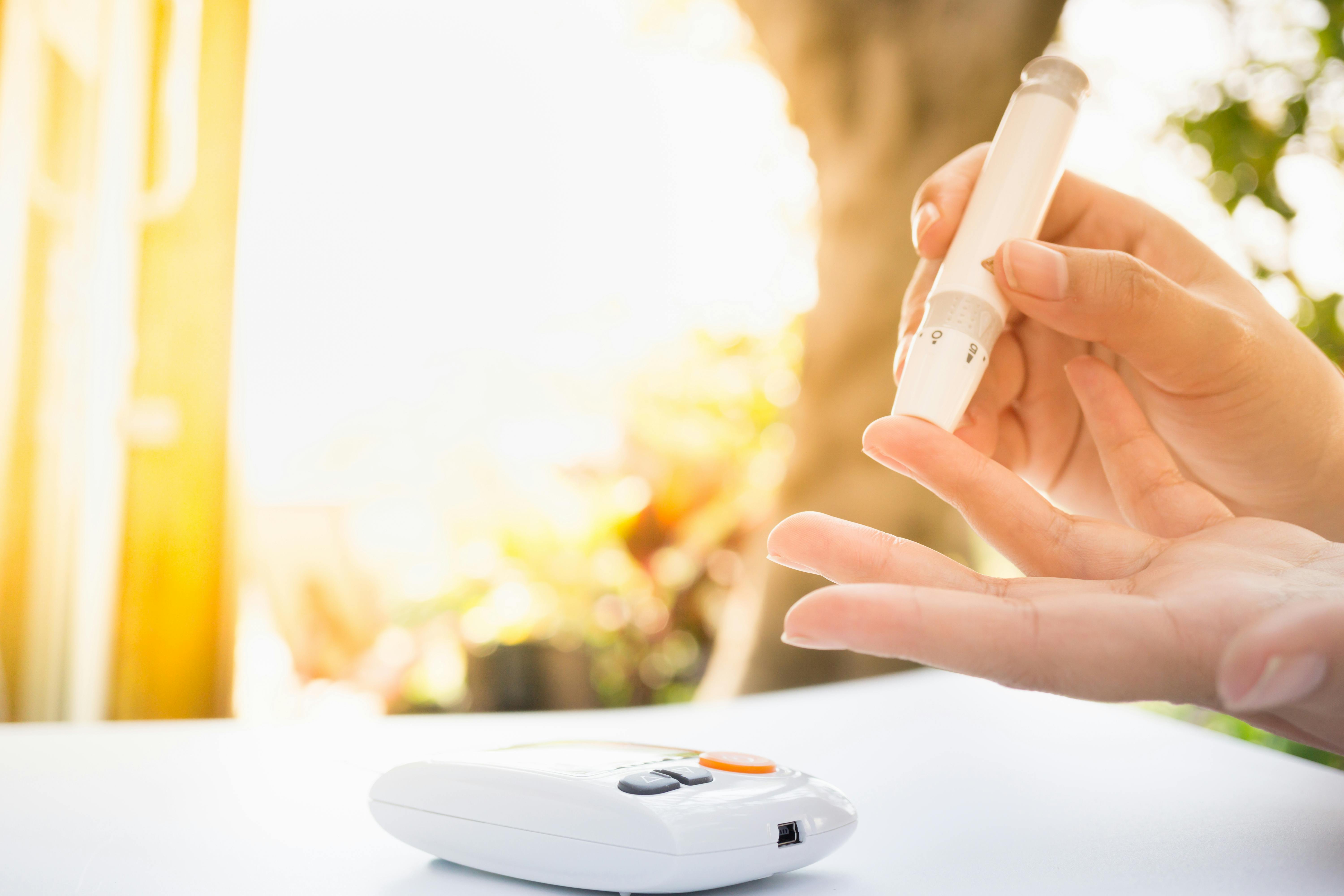 Medicine, Diabetes, Glycemia, Health care and people concept – close up of female using lancelet on  finger to checking blood sugar level by Glucose meter